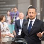 Bărbat în costum susține un discurs la microfon