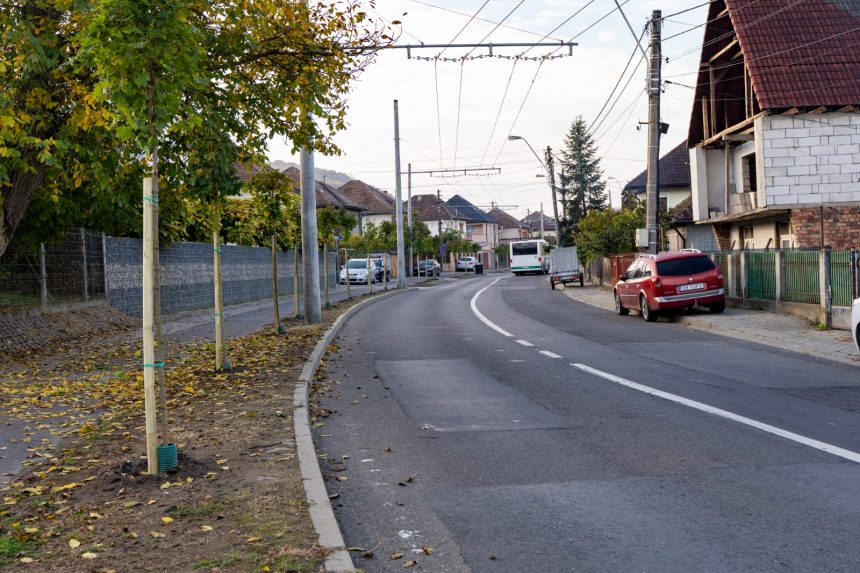 Stradă rezidențială cu autobuz, mașini și trotuare noi