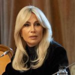 Femeie blondă la o masă de conferință cu microfon