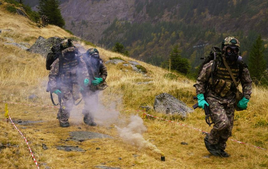 Militari cu măști antigaz într-un exercițiu montan