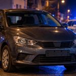 Mașină gri oprită noaptea, cu poliția în fundal