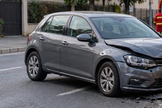 Mașină gri avariată în partea frontală după accident