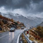 Mașini pe șosea montană udă, sub nori de furtună