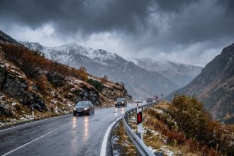 Mașini pe șosea montană udă, sub nori de furtună