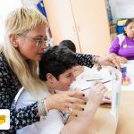 Femeie sprijinind un copil la pictură într-un atelier
