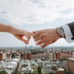 Mireasă și mire ținându-se de mâini deasupra orașului