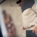 Persoană cu fața acoperită privind ecranul unui telefon