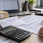 Calcul TVA cu documente, calculator și laptop pe birou
