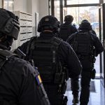 Polițiști mascați intră într-o clădire rezidențială