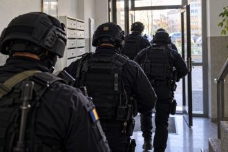 Polițiști mascați intră într-o clădire rezidențială