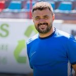 Bărbat zâmbitor în tricou albastru pe stadion