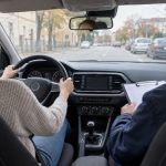 Cursantă conduce mașina alături de instructor auto