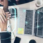 Echipă de afaceri cu mâinile suprapuse lângă laptopuri