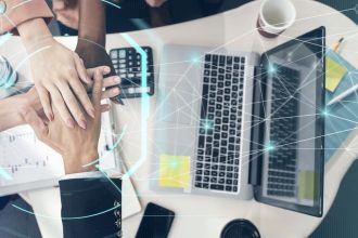 Echipă de afaceri cu mâinile suprapuse lângă laptopuri