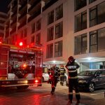 Pompieri intervenind noaptea lângă un bloc de locuințe