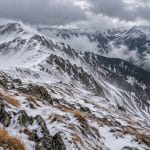 Creste montane înzăpezite sub nori dramatici
