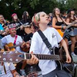 Participanți cântând la chitare într-un festival în aer liber