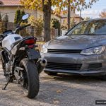 Motocicletă și autoturism gri parcate pe stradă