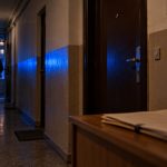 Persoană în hol de bloc luminat de girofar albastru