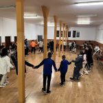 Copii și adolescenți dansează în cerc într-o sală