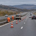 Lucrători întrețin parapetul pe autostradă, printre conuri