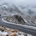 Drum montan șerpuit, acoperit de zăpadă, prin ceață