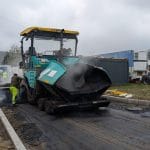 Muncitori asfaltează o stradă cu finisorul